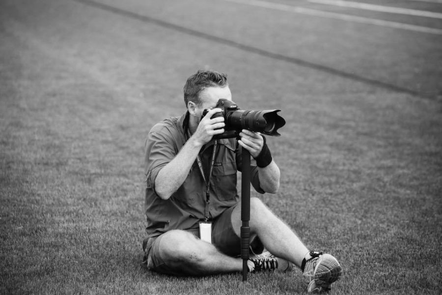 Colin Murphy taking photos on a hill during a sporting event. Murphy enjoys just going to games and being in the atmosphere. “I love sports, always have and always will,” Murphy said. 