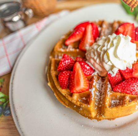 Big Belgian Waffles with powdered sugar, strawberries, and maple bourbon butter.