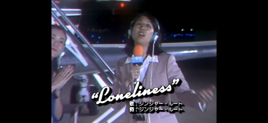 The photo is a screenshot from the official Loneliness music video, where Cameron Lew (Ginger Root) performs a song that quitting artist Kimiko is originally supposed to sing. The year is 1983, Ginger Root is asked to write and produce songs for up-and-coming Japanese Idol, Kimimo Takeguchi. Right before Kimiko’s America Debut, she quits, leaving her manager to make the last minute decision of having Ginger Root perform in her place since he knows all the songs, Genius contributor Tappeh and gingerrootmusic.com  said. By coincidence, a new star is born.