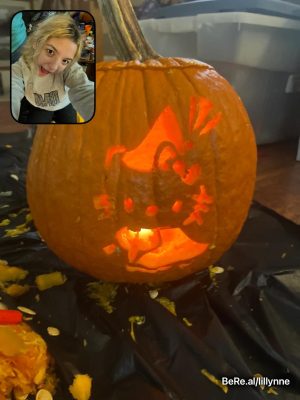 A pumpkin carved with the Sanrio character Hello Kitty and Madelynne Earhart showing it off