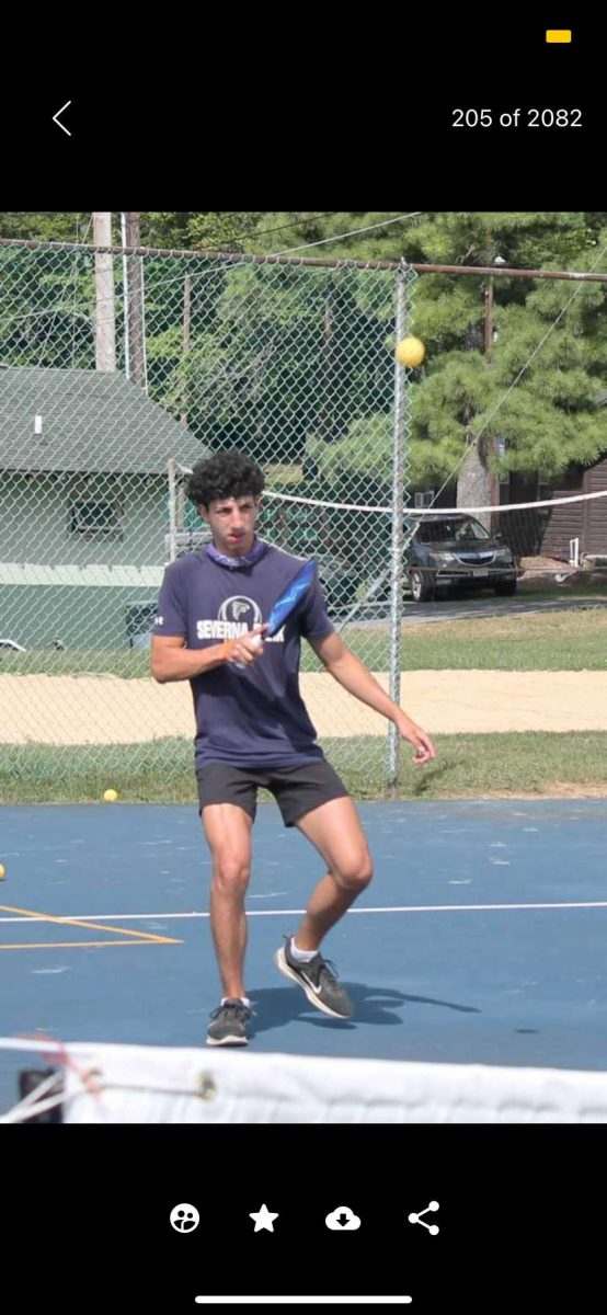 Jake Smulow, President of the Severna Park High School pickleball club, volleying the pickleball back over the net. 