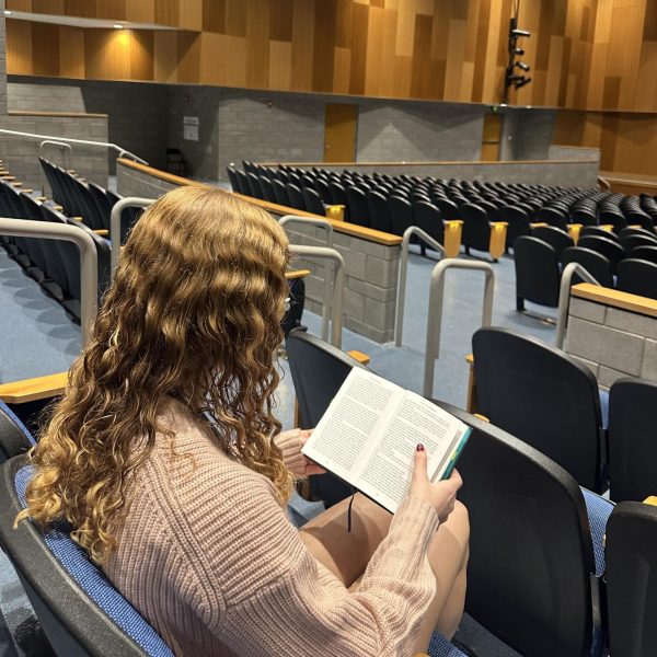 Junior Jolene Robertson reads her English book in the auditorium  during Gold Block. “They used to be a  little more lenient on talking in the auditorium but then it got to be too much, so they made it a fully quiet zone for studying which I like a lot more,” Robertson said. It is also required to present your grades to a teacher prior to entering the auditorium for Falcon Block.