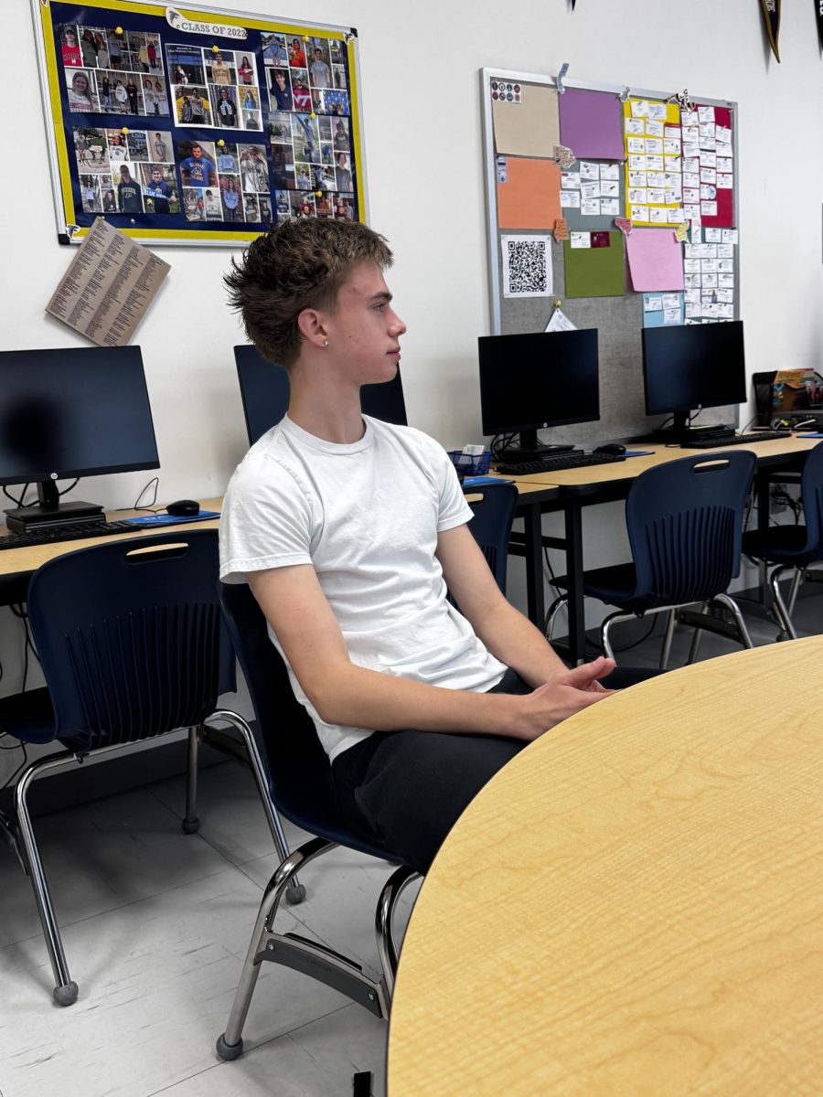 Senior, Alex Kinross paying attention to the presentation from Dan Zawacki, a Towson adviser. His attentiveness is shown through him being quiet and paying attention to the speaker's words.