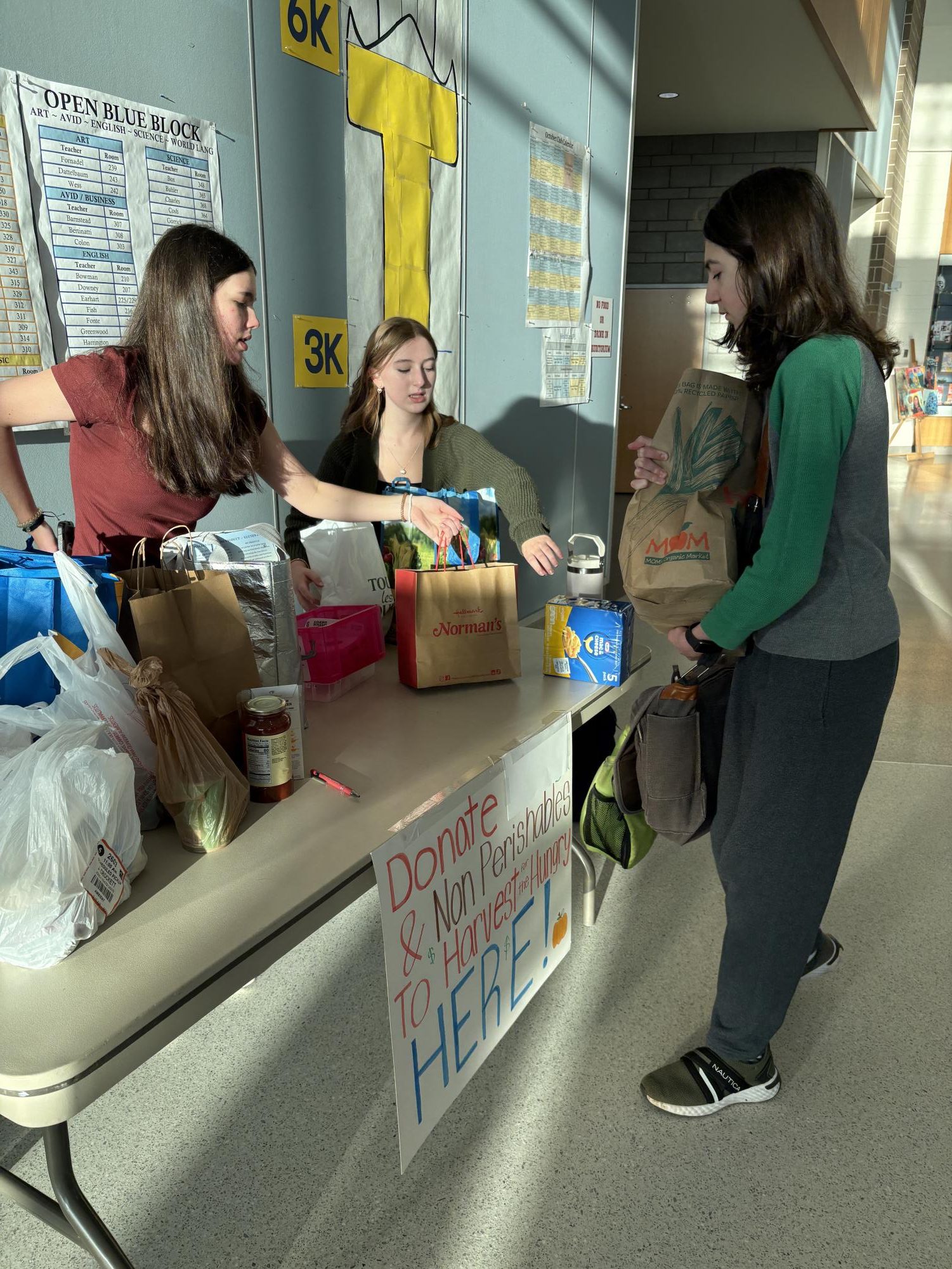 Senior Violet Thompson and sophomore Paige Williams at the Harvest for the Hungry food donations booth helping a student donate before classes started on Oct. 22. In addition to students donating monetary donations directly to their 1A as a part of the 1A bracket competition, students are able to donate to Harvest for the Hungry with non-perishable food donations. “Harvest for the Hungry is a county wide initiative that is kind of like a competition between schools, too, where they invite all the schools to raise a bunch of money and or raise a bunch of food,” Williams said. “Some schools do pounds of food. We are one of the schools that takes monetary and food donations.”